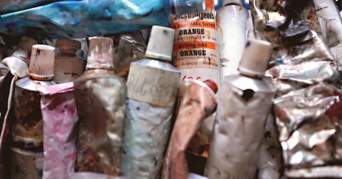 Une collection de tubettes de peinture usagées et colorées, montrant texture et créativité dans l'espace de travail d'un artiste.